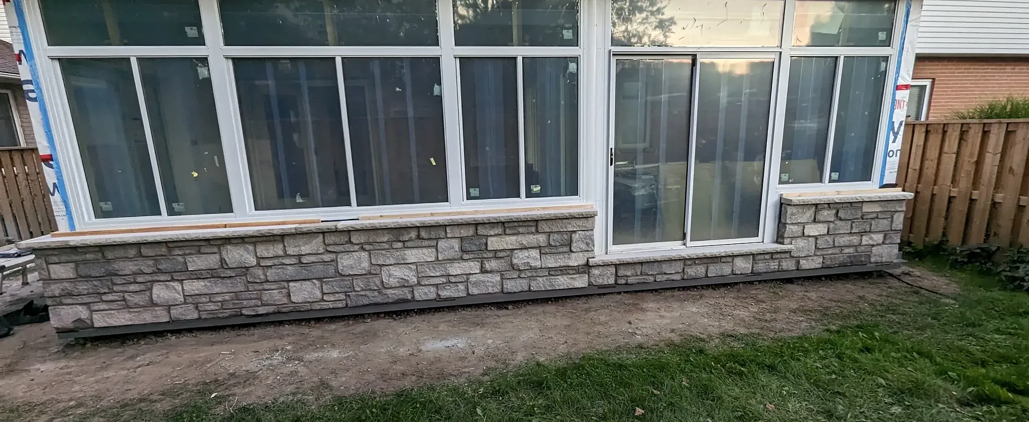 Sunroom addition with a natural stone base and large windows