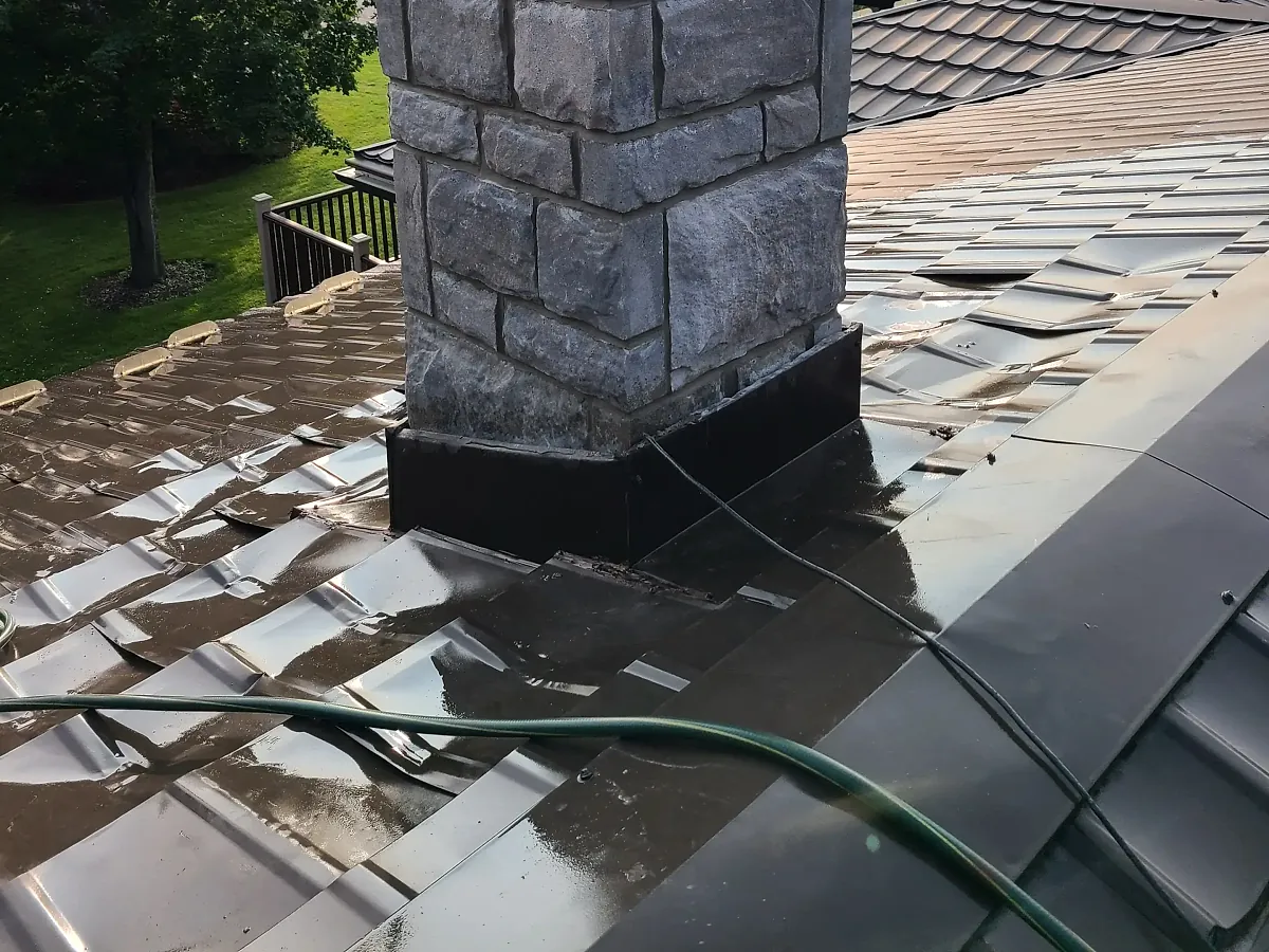 Stone chimney stack with newly installed flashing on a metal roof