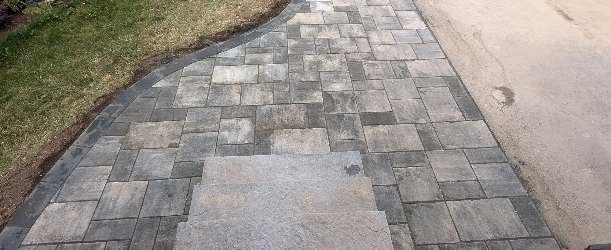 Interlock paver walkway curving from a driveway to a front door