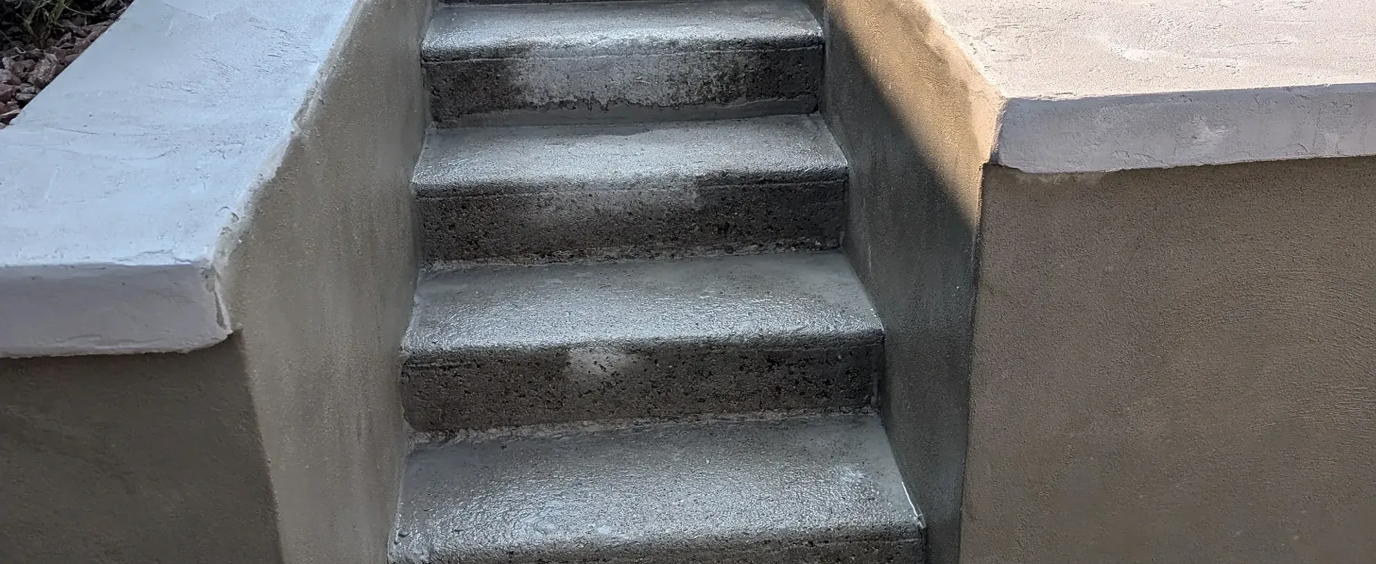 Poured concrete steps running alongside a low stone wall