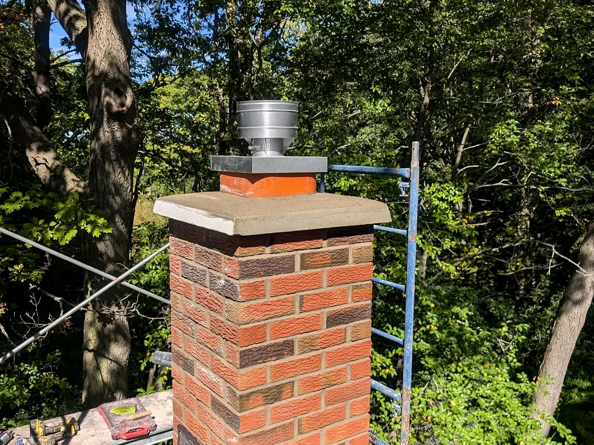 Rebuilt red brick chimney with a new concrete crown and stainless cap
